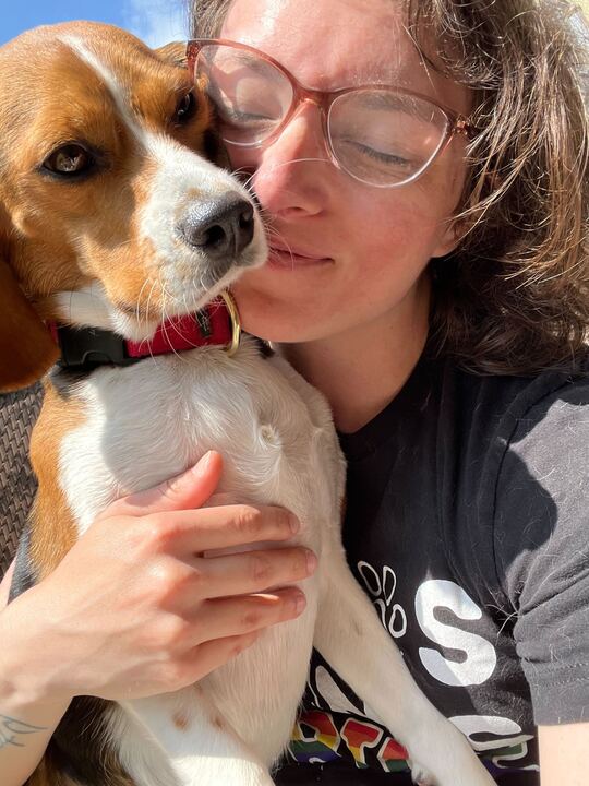 Close up of Daycare attendant at Puptown Lounge North Columbus snuggling a small beagle in the sun